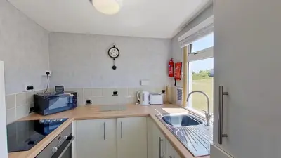 a kitchen with a sink and a clock on the wall at F04 Penrhys, Rivere Towans in Hayle