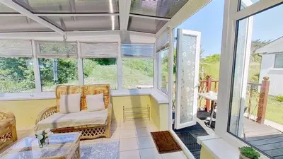 a screened in porch with a chair and a table at F04 Penrhys, Rivere Towans in Hayle