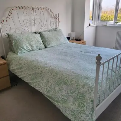 a white bed with a blue comforter and two pillows at House in Cornwall in Redruth