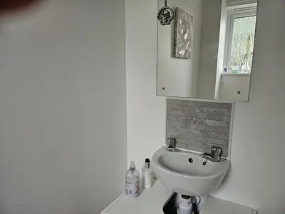 a white bathroom with a sink and a cabinet at House in Cornwall in Redruth