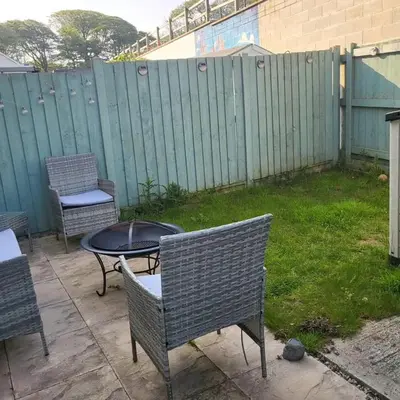 a patio with chairs and a table and a fence at House in Cornwall in Redruth