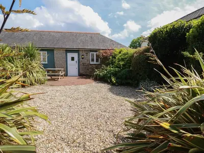 a cottage with a bench in a garden at The Copper House in Truro