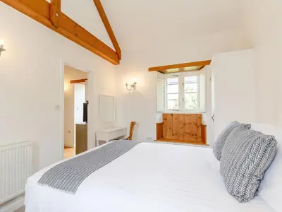 a white bedroom with a white bed and a window at The Copper House in Truro