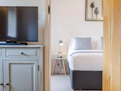 a bedroom with a bed and a flat screen tv at The Copper House in Truro