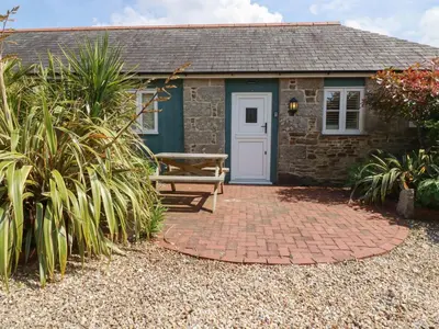 a stone cottage with a picnic table in front of it at The Copper House in Truro