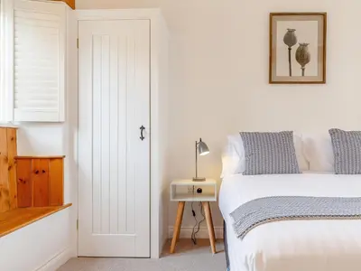 a bedroom with a bed and a table with a lamp at The Copper House in Truro