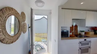 a kitchen with white cabinets and a mirror on the wall at D26 Vu-An-Tecca, Riviere Towans in Hayle