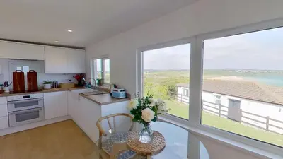 a kitchen with a table with a vase of flowers on it at D26 Vu-An-Tecca, Riviere Towans in Hayle