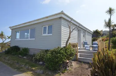 a small white house with two chairs on the porch at D26 Vu-An-Tecca, Riviere Towans in Hayle