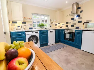 a kitchen with blue cabinets and a bowl of fruit on a table at Little Acorns in Helston