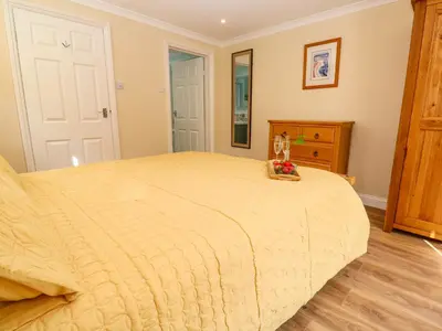 a bedroom with a large bed and a wooden dresser at Little Acorns in Helston