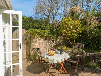 a patio with a table and chairs and a door at Little Acorns in Helston