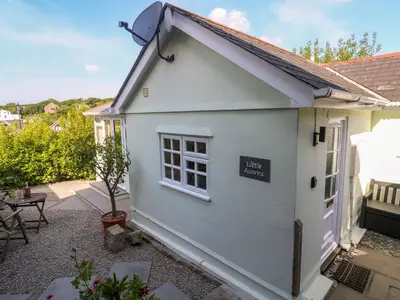a white cottage with a small window and a patio at Little Acorns in Helston