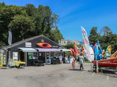 a group of people standing in front of a market with surfboards at 5 Esplanade in Fowey