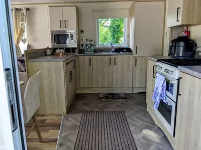 a kitchen with wooden cabinets and a stove top oven at 63 The Lea with decking Trevella Holiday Park in Crantock