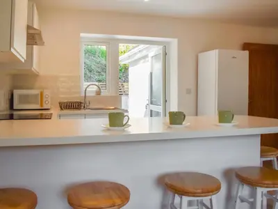a kitchen with a counter with stools and a refrigerator at 3 Le Dorney Villa - Uk49820 in Par