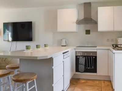 a kitchen with white cabinets and a counter with stools at 3 Le Dorney Villa - Uk49820 in Par