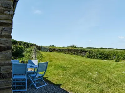 two blue chairs sitting next to a field of grass at Carriage House in Mawgan Porth