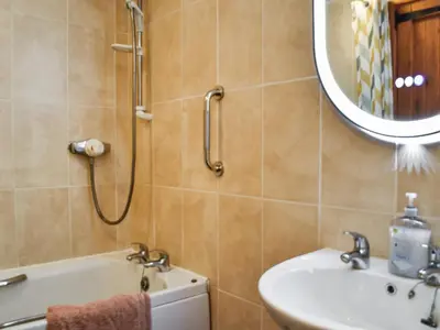a bathroom with a shower and a sink and a mirror at Carriage House in Mawgan Porth
