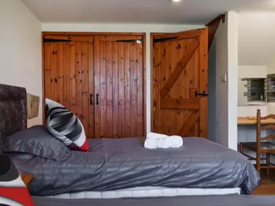 a bedroom with a bed with a wooden door at Carriage House in Mawgan Porth