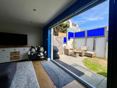 a living room with a large sliding glass door at Pufflings, Padstow Coastal Cottage, Free Private Parking in Padstow