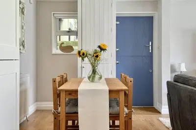 a dining room table with a vase of flowers on it at Pufflings, Padstow Coastal Cottage, Free Private Parking in Padstow