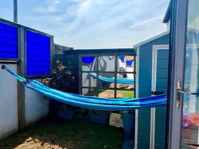 a blue hammock on the side of a house at Pufflings, Padstow Coastal Cottage, Free Private Parking in Padstow