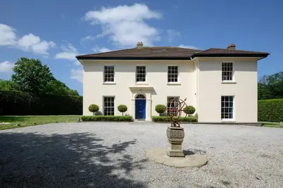 a large white house with a blue door at The Vicarage - Grand Country House, Walking Distance to Padstow and with Pub Across the Road in Wadebridge