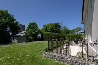 a fence in a yard next to a house at The Vicarage - Grand Country House, Walking Distance to Padstow and with Pub Across the Road in Wadebridge