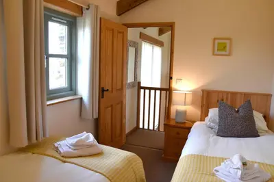 a bedroom with two beds and a window and a door at Ash Cottage, 3 bed large cottage in Tregoney