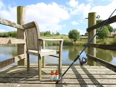 a rocking chair and bottles of beer on a dock at Ash Cottage, 3 bed large cottage in Tregoney