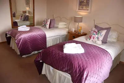 a hotel room with two beds with purple blankets at Ash Cottage, 3 bed large cottage in Tregoney