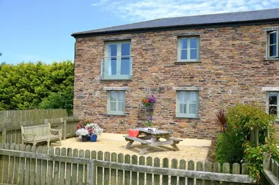 a brick house with a picnic table and a wooden fence at Ash Cottage, 3 bed large cottage in Tregoney
