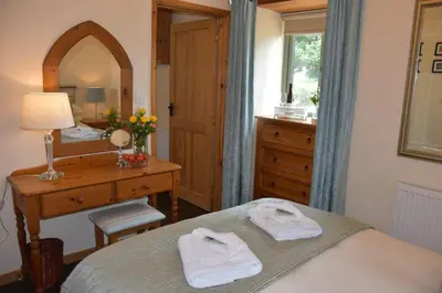 a bedroom with a bed and a desk and a mirror at Beech cottage is a beautiful 1 bed cottage in Saint Ewe