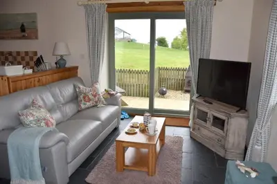a living room with a couch and a flat screen tv at Beech cottage is a beautiful 1 bed cottage in Saint Ewe