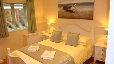 a bedroom with a white bed with towels on it at Elm Cottage Delightful 2 bed accessible holiday cottage in Tregoney