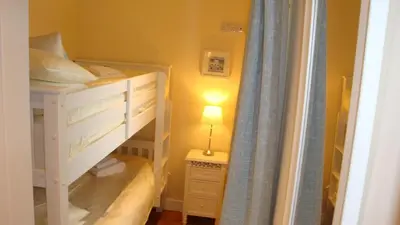 a bedroom with a bunk bed with a lamp on a table at Elm Cottage Delightful 2 bed accessible holiday cottage in Tregoney