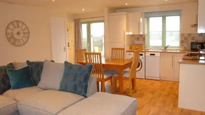 a living room with a couch and a table and a kitchen at Elm Cottage Delightful 2 bed accessible holiday cottage in Tregoney