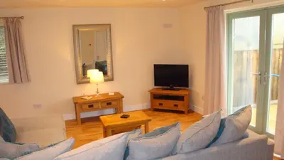 a living room with a couch and a television at Elm Cottage Delightful 2 bed accessible holiday cottage in Tregoney