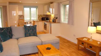 a living room with a couch and a kitchen at Elm Cottage Delightful 2 bed accessible holiday cottage in Tregoney