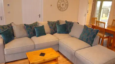 a living room with a gray couch with blue pillows at Elm Cottage Delightful 2 bed accessible holiday cottage in Tregoney