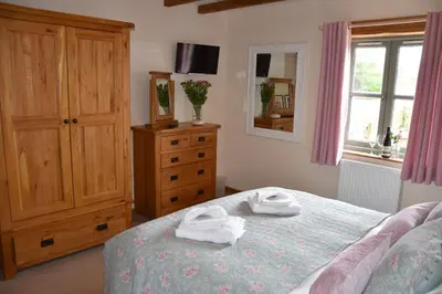 a bedroom with a bed and a dresser with towels on it at Hawthorn Cottage Luxury stone Built Cottage in Tregoney