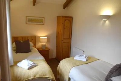 a bedroom with two beds with towels on them at Hawthorn Cottage Luxury stone Built Cottage in Tregoney
