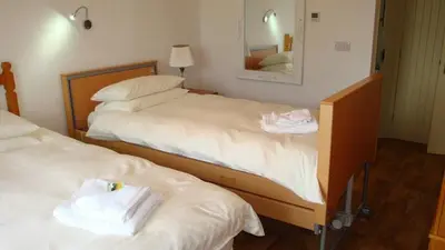 two beds in a hotel room with towels on them at Hazel - 3 Bed accessible holiday cottages in Tregoney