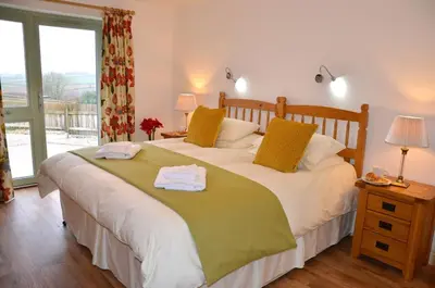 a bedroom with a large bed with towels on it at Hazel - 3 Bed accessible holiday cottages in Tregoney