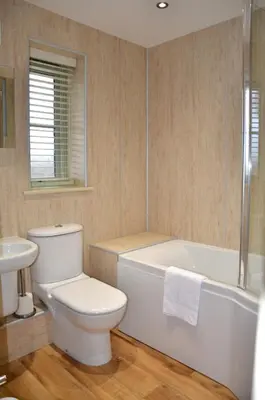 a bathroom with a toilet and a tub and a sink at Hazel - 3 Bed accessible holiday cottages in Tregoney
