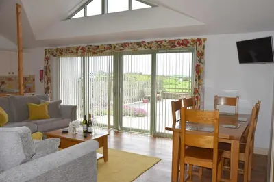 a living room with a couch and a dining room at Hazel - 3 Bed accessible holiday cottages in Tregoney