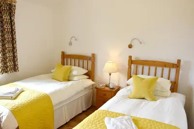 a bedroom with two beds with yellow pillows at Hazel - 3 Bed accessible holiday cottages in Tregoney