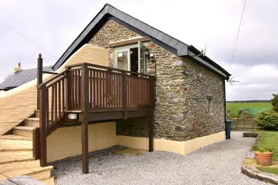 a house with a balcony and a deck at Oak Cottage in Tregoney