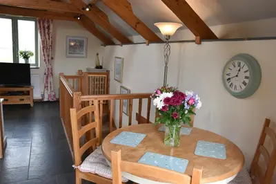 a dining room table with a vase of flowers on it at Oak Cottage in Tregoney